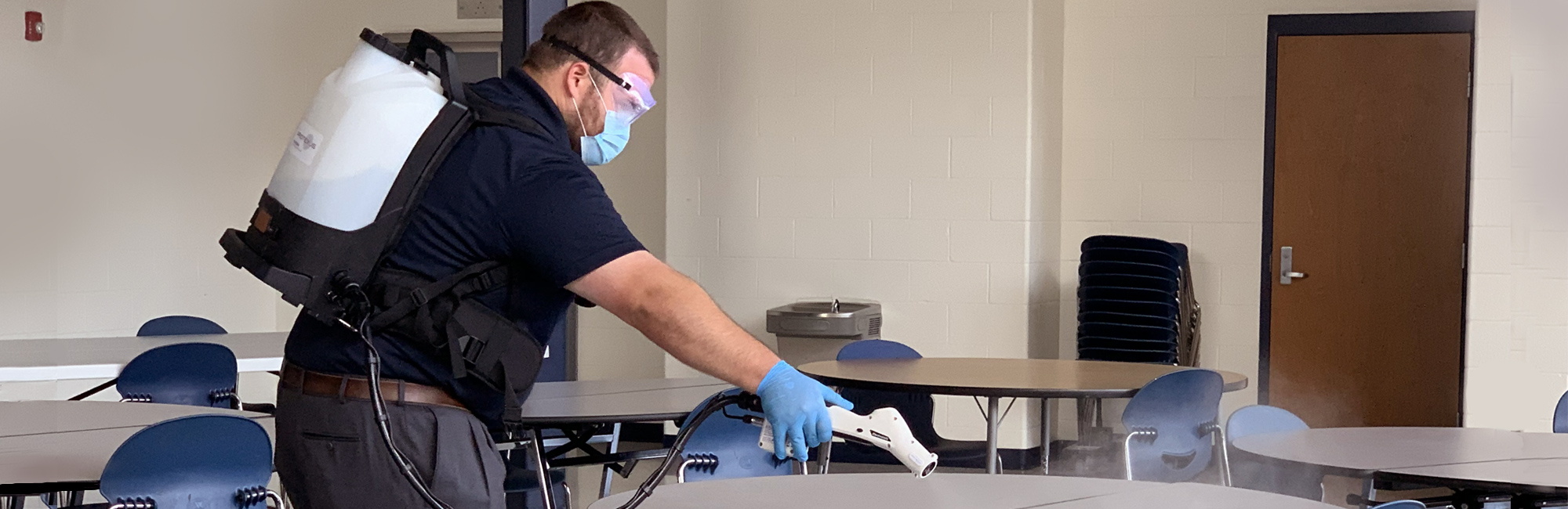 a man wearing a mask and gloves in a classroom