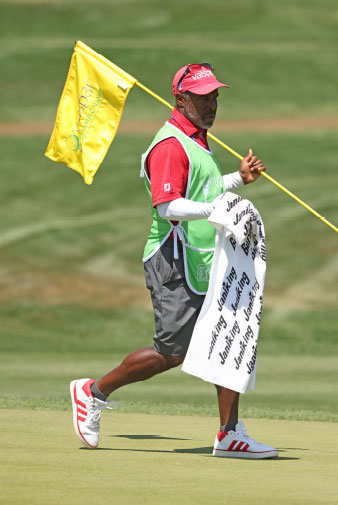 a man holding a flag and walking on a golf course