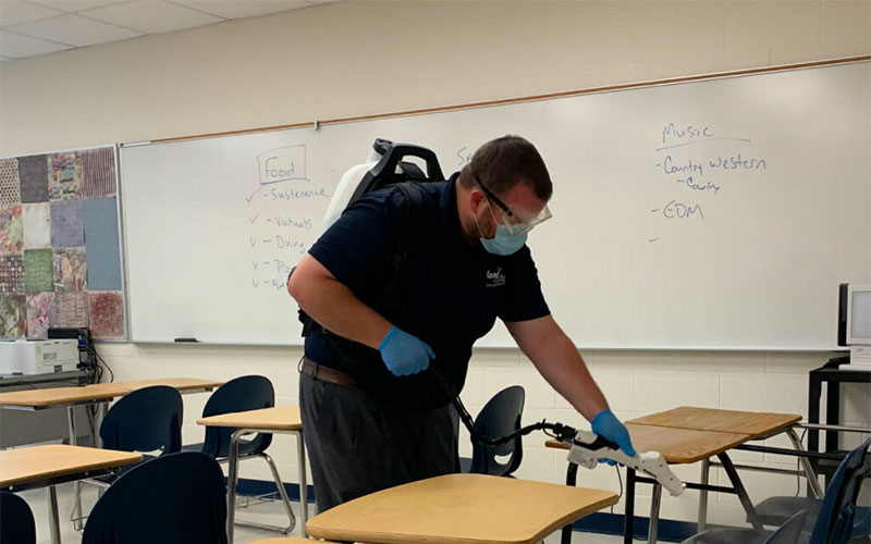 a man in a classroom wearing a mask and gloves